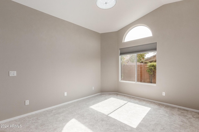 empty room with lofted ceiling, light colored carpet, and baseboards