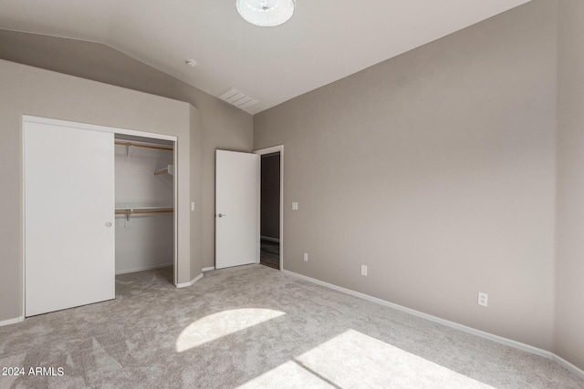 unfurnished bedroom featuring light carpet, baseboards, visible vents, vaulted ceiling, and a closet