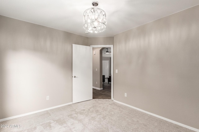 unfurnished room featuring carpet flooring, baseboards, and ceiling fan with notable chandelier