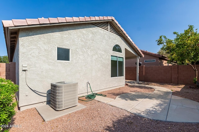 back of property with a fenced backyard, central air condition unit, a tile roof, stucco siding, and a patio area