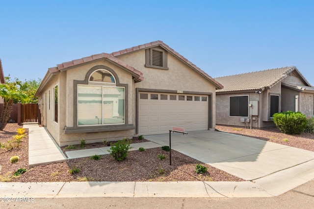 single story home with an attached garage, fence, a tile roof, concrete driveway, and stucco siding