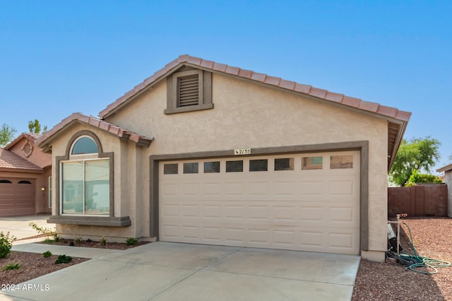 view of front of house with a garage, a tiled roof, concrete driveway, and stucco siding