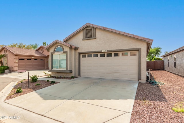 view of front facade featuring a garage, concrete driveway, a tile roof, and stucco siding