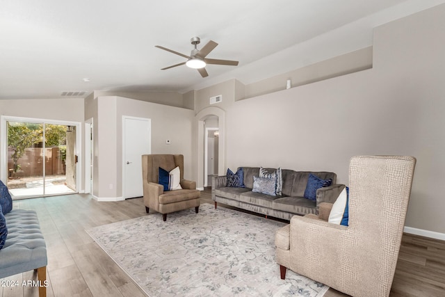 living room featuring lofted ceiling, visible vents, and wood finished floors