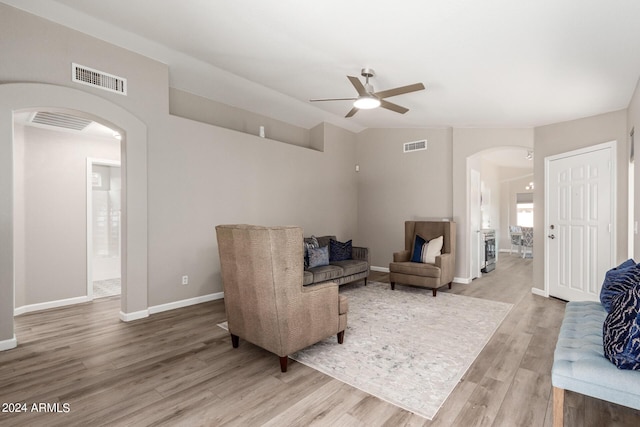 living area with arched walkways, vaulted ceiling, wood finished floors, and visible vents