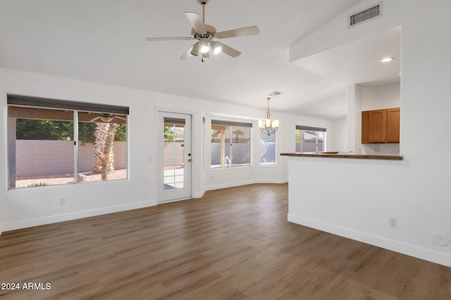 unfurnished living room featuring lofted ceiling, dark wood-type flooring, and ceiling fan with notable chandelier