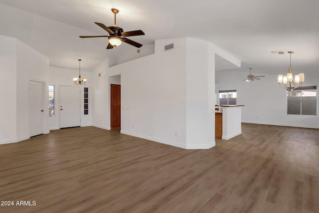 unfurnished living room featuring a wealth of natural light, dark hardwood / wood-style floors, ceiling fan with notable chandelier, and high vaulted ceiling