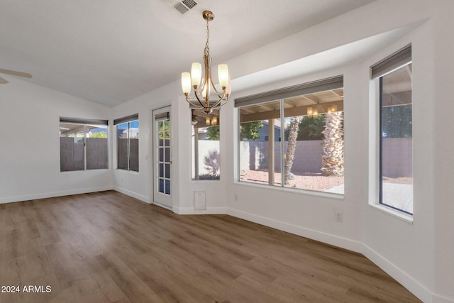 unfurnished dining area with wood-type flooring, vaulted ceiling, and a chandelier