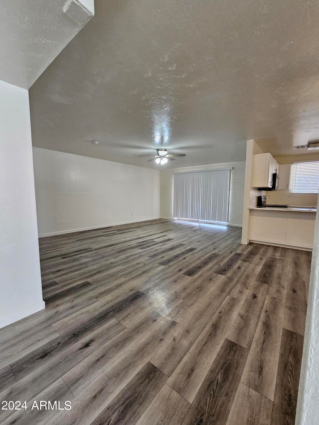 bonus room with a textured ceiling, dark wood-type flooring, and ceiling fan