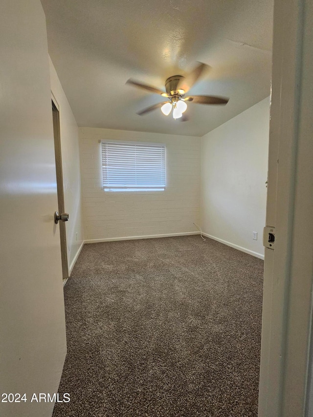 spare room with dark carpet, brick wall, a textured ceiling, and ceiling fan