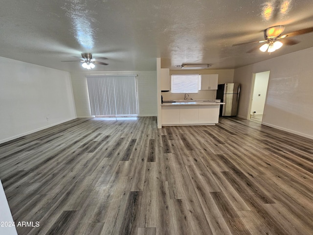 unfurnished living room with ceiling fan, a textured ceiling, sink, and dark hardwood / wood-style floors