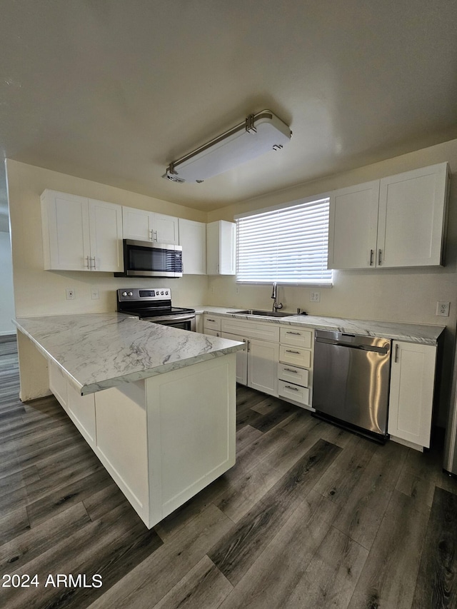 kitchen featuring appliances with stainless steel finishes, kitchen peninsula, white cabinetry, and dark hardwood / wood-style flooring