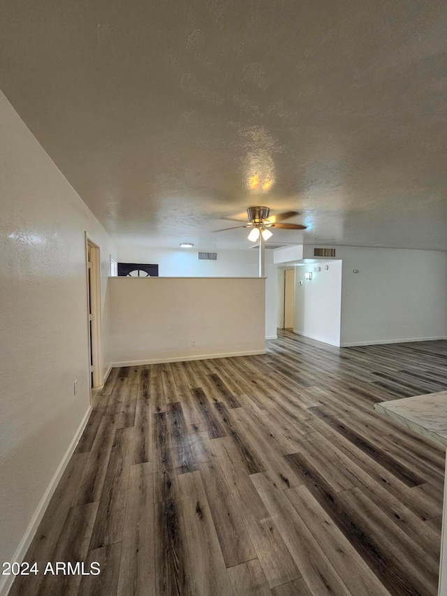 unfurnished living room with ceiling fan, a textured ceiling, and dark hardwood / wood-style floors