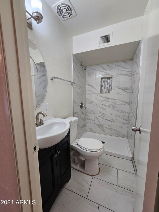 bathroom featuring vanity, toilet, and tiled shower