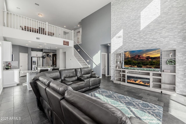 living room featuring built in shelves, a high ceiling, and a stone fireplace