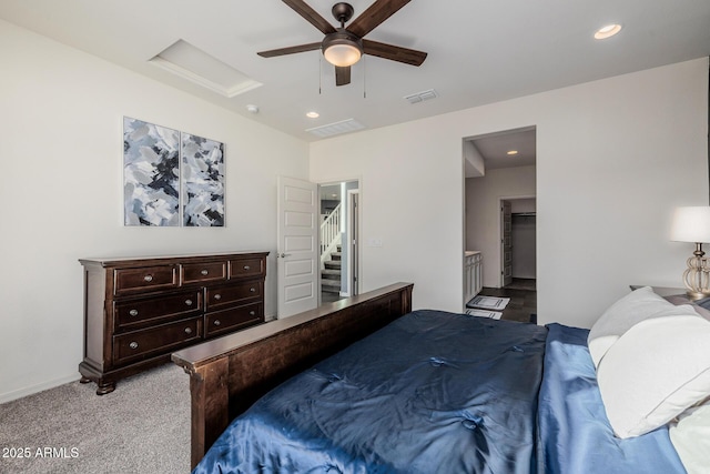 bedroom featuring ceiling fan, light colored carpet, ensuite bathroom, and a spacious closet