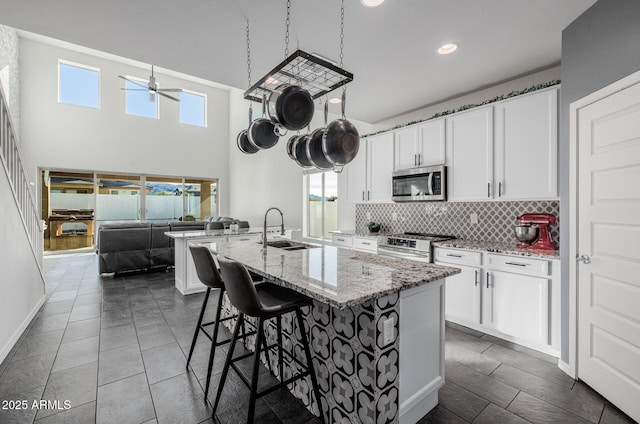 kitchen with sink, stainless steel appliances, white cabinets, and light stone countertops