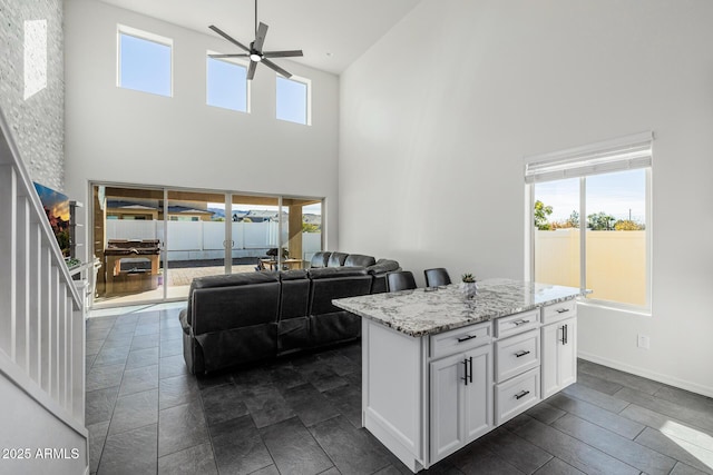 kitchen featuring light stone counters, white cabinets, and a towering ceiling