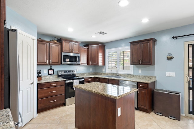 2185 E Gillcrest Rd, Gilbert, AZ 85298 - kitchen with appliances with stainless steel finishes, a sink, light stone counters, a center island, and light tile patterned flooring
