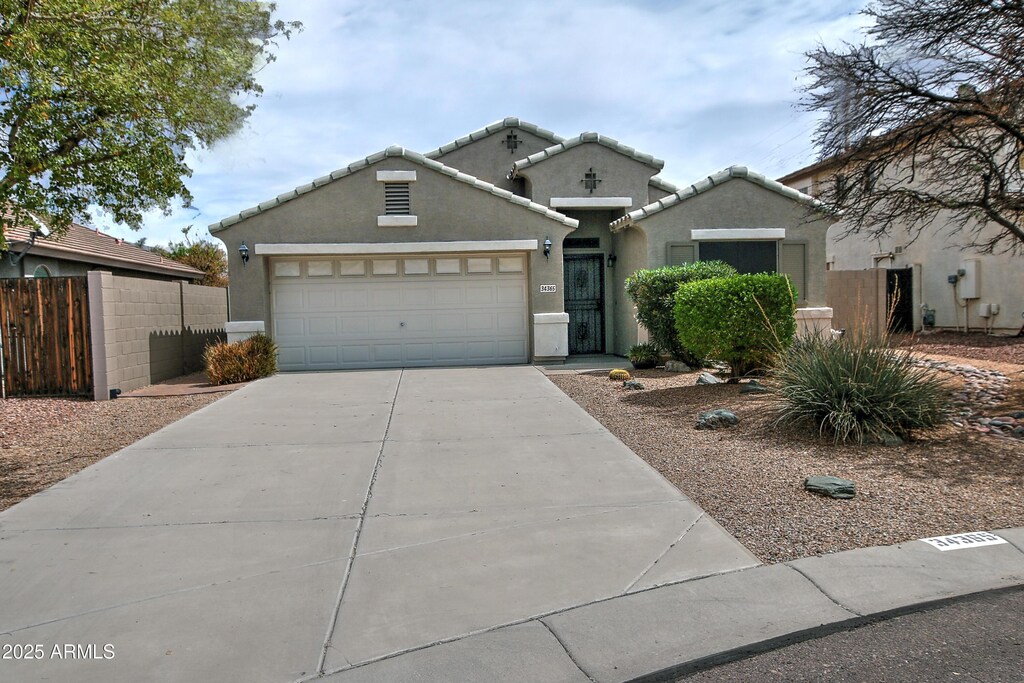 view of front of property with a tile roof, concrete driveway, stucco siding, fence, and a garage