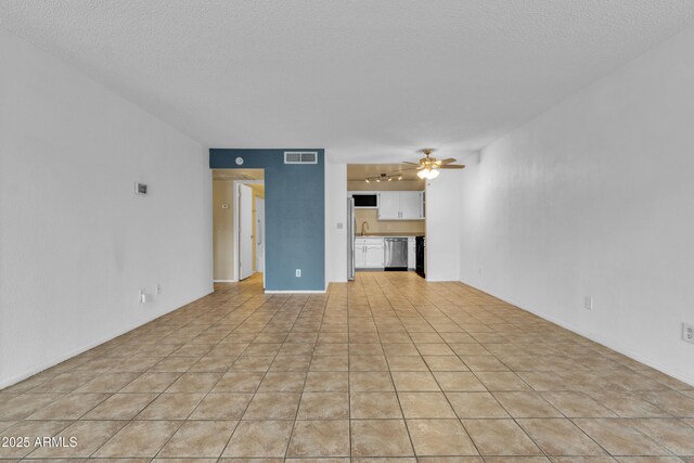 unfurnished living room with visible vents, a ceiling fan, a sink, light tile patterned floors, and a textured ceiling