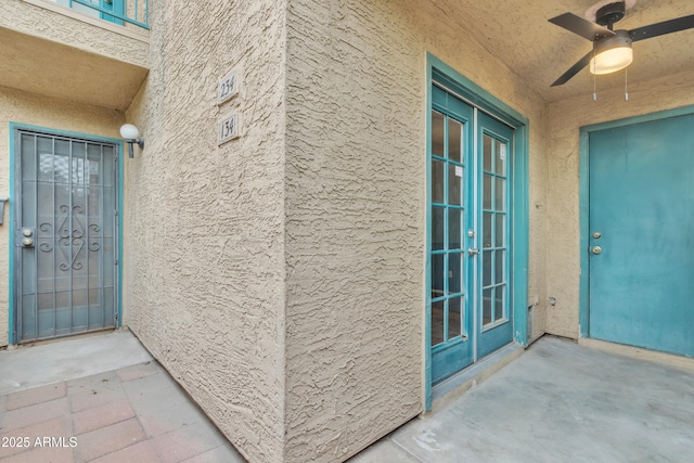 doorway to property featuring stucco siding, a ceiling fan, and french doors