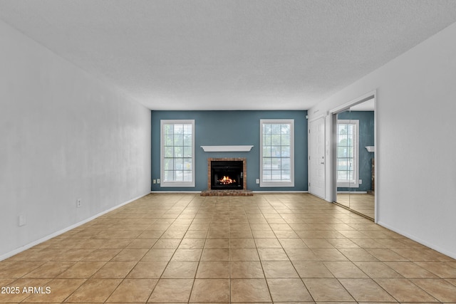 unfurnished living room featuring baseboards, a fireplace, and light tile patterned flooring