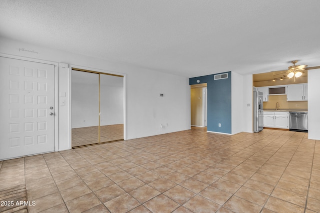 unfurnished living room with a ceiling fan, a textured ceiling, and visible vents