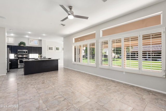 kitchen featuring decorative backsplash, stainless steel appliances, vaulted ceiling, ceiling fan, and a kitchen island