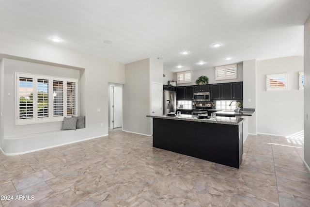 kitchen featuring sink, an island with sink, appliances with stainless steel finishes, tasteful backsplash, and light stone counters