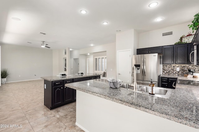 kitchen with light stone countertops, sink, ceiling fan, stainless steel appliances, and tasteful backsplash