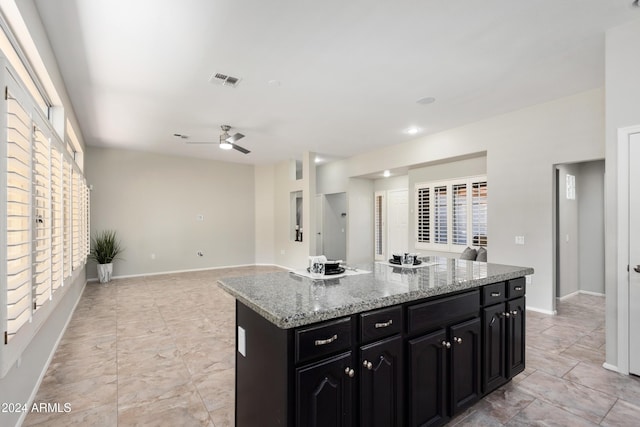 kitchen featuring light stone countertops, a kitchen island, and ceiling fan