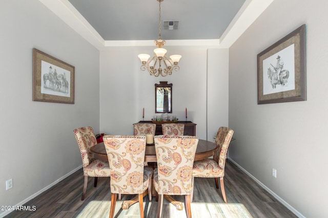 dining space featuring a tray ceiling, dark wood-type flooring, and a chandelier