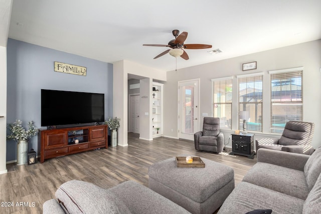 living room featuring ceiling fan, wood-type flooring, and built in shelves