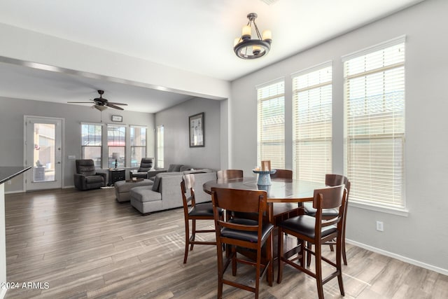 dining space with wood-type flooring and ceiling fan with notable chandelier