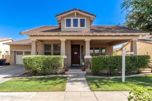 view of front of home featuring covered porch, a garage, and a front yard