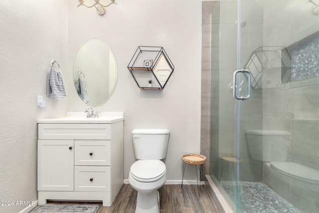 bathroom featuring vanity, wood-type flooring, a shower with shower door, and toilet