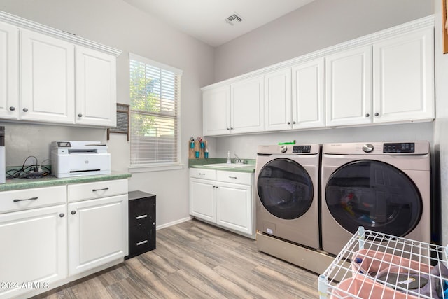 laundry area featuring washing machine and dryer, sink, and light hardwood / wood-style floors