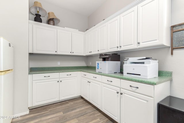 kitchen with white cabinets, wood-type flooring, and white fridge