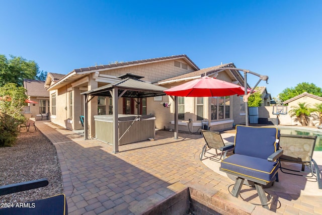 back of house with a gazebo, a hot tub, and a patio area