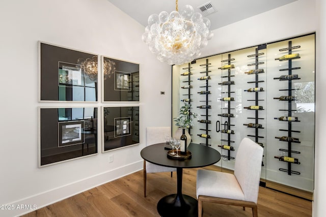 wine room with wood-type flooring and a notable chandelier