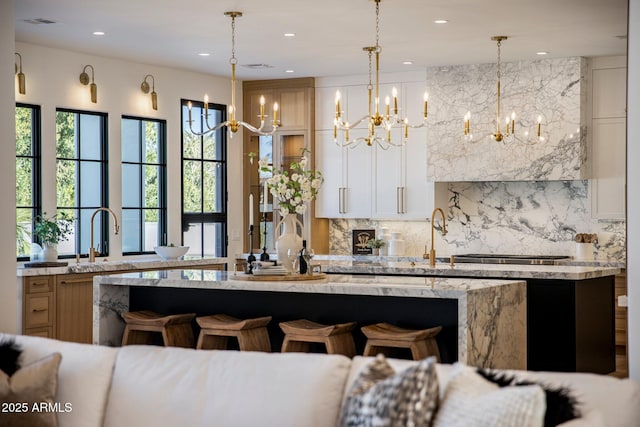 kitchen featuring tasteful backsplash, decorative light fixtures, a breakfast bar area, and light stone countertops