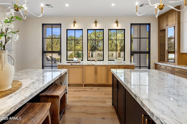 kitchen with light stone countertops, a chandelier, and light hardwood / wood-style flooring