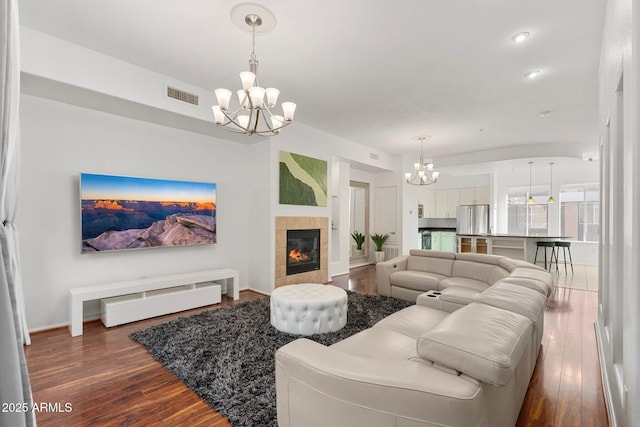 living room with a tiled fireplace, dark hardwood / wood-style floors, and an inviting chandelier