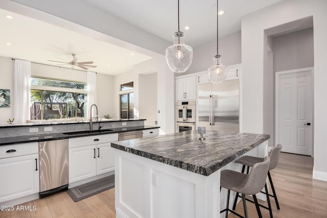 kitchen featuring appliances with stainless steel finishes, ceiling fan, white cabinets, and sink