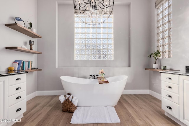 bathroom featuring vanity, hardwood / wood-style flooring, a chandelier, and a bathtub