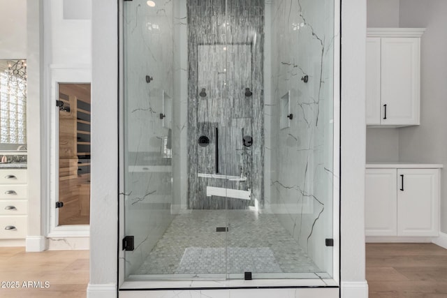 bathroom with a shower with door and hardwood / wood-style floors