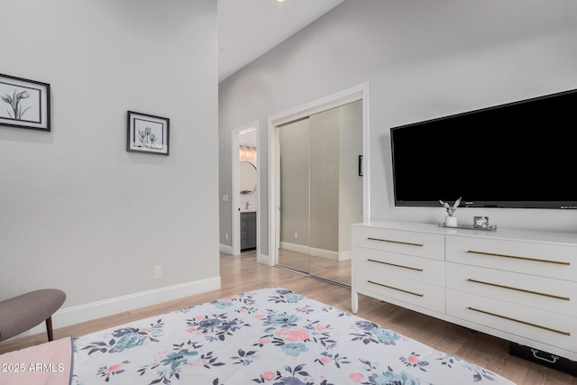 bedroom with lofted ceiling, light wood-type flooring, and a closet