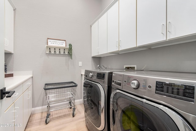 laundry room with washer and clothes dryer, light hardwood / wood-style floors, and cabinets