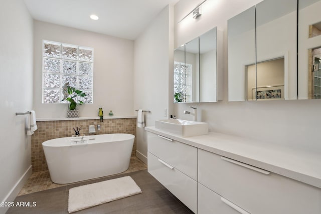 bathroom with vanity, tile walls, and a bathtub